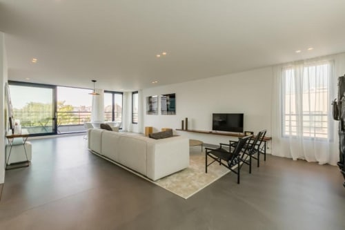 Appartement loft moderne au Livorno, Bruxelles avec canapé crème, chaises noires, TV et baies vitrées panoramiques