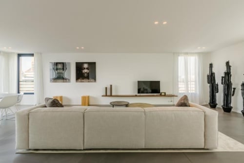 Élégant penthouse à Bruxelles avec canapé sectionnel crème, téléviseur mural et décoration minimaliste