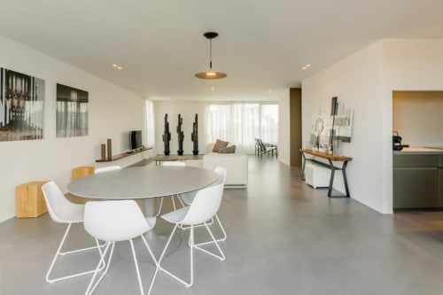 Loft moderne au Livorno Brussels avec table de salle à manger ronde, chaises blanches et espace de vie ouvert