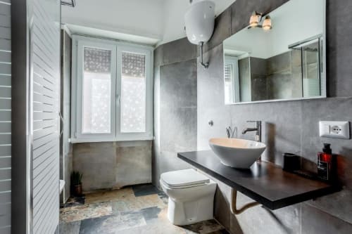 Moderno bagno dell'Amor Rome Apartment con lavabo a bacinella, piastrelle grigie, toilette e finestra a Roma