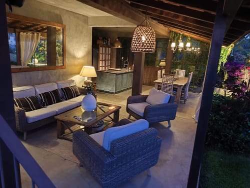 Patio lounge de Les Terrasses Suites en Calheta, PT con asientos de mimbre, iluminación colgante y vistas al jardín