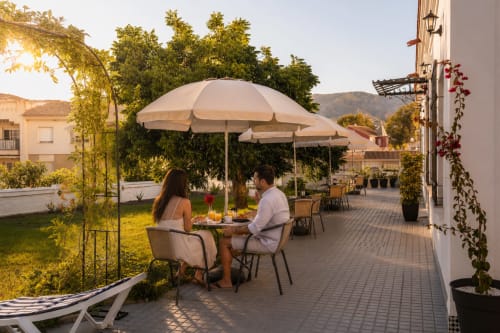 Pareja cenando bajo sombrilla en la terraza del Hotel Boutique Alcazaba Salobreña con vistas a la montaña