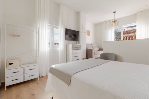 Habitación moderna del hotel Alcazaba Salobreña con mobiliario blanco, TV de pantalla plana e iluminación natural abundante