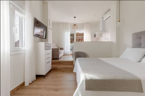 Habitación moderna del hotel Alcazaba Salobreña con cama, cocina y vistas al campo de Granada