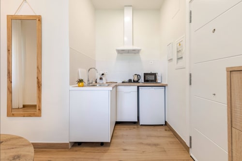 Kitchenette moderno en Hotel Boutique Alcazaba Salobreña con electrodomésticos blancos, encimeras de madera y espejo en Granada