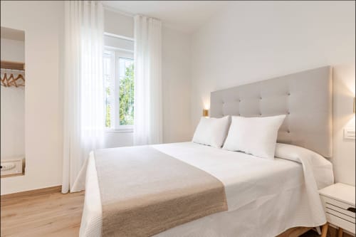 Dormitorio moderno y luminoso en Hotel Boutique Alcazaba Salobreña con cabecero tapizado, sábanas blancas y luz natural