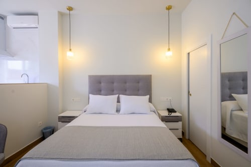 Habitación moderna en Hotel Boutique Alcazaba de Salobreña con cabecero gris, lámparas colgantes y armario espejado