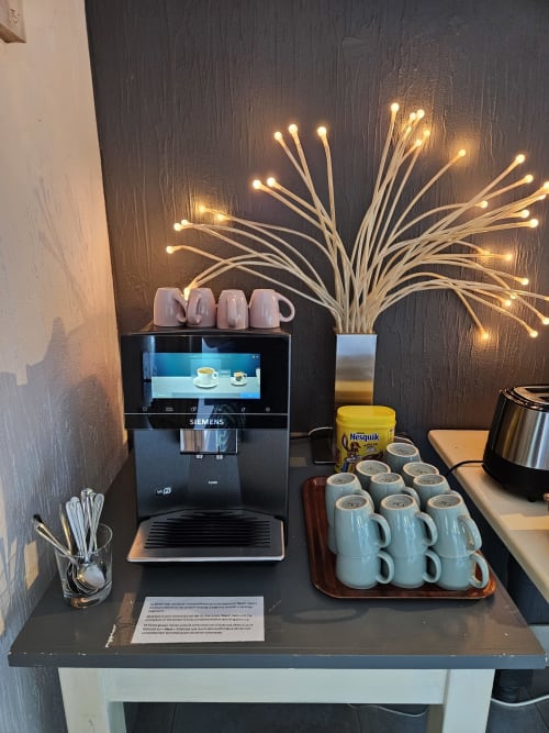 Coffee station at Les Alisiers B&B in Nadrin with Siemens machine, mugs, and illuminated decorative plant