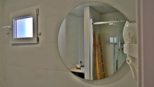Baño moderno en Cal Xot B&B en Poble Nou con espejo redondo, ducha de cristal y pequeña ventana