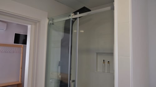 Ducha moderna con puerta de cristal y alcachofa de lluvia en habitación de Cal Xot BnB, Poble Nou Barcelona