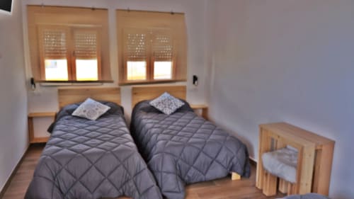 Habitación cuádruple de Cal Xot B&B en Poble Nou con dos camas, ventanas de madera y luz natural