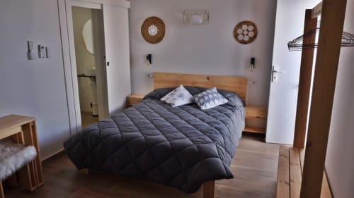 Dormitorio Cal Xot en Poble Nou con cama de madera, ropa de cama oscura, cestas decorativas en la pared y comodidades modernas