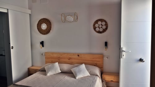 Dormitorio Cal Xot en Poble Nou con cama de madera, cestos decorativos en la pared y servicios modernos como TV y WiFi