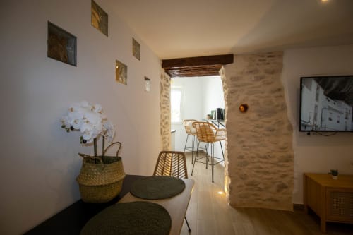 Modern apartment entryway in Setenil de las Bodegas with stone archway, white orchid plant, and bar seating visible through