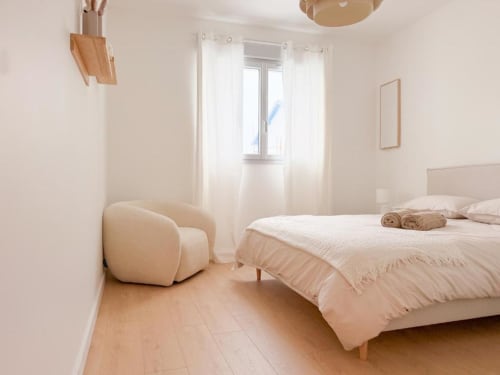 Helles, minimalistisches Schlafzimmer im Vindihouses B&B in Epinac mit cremefarbenem Sessel, Holzböden und natürlichem Licht