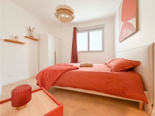 Helles modernes Schlafzimmer im Vindihouses B&B in Épinac mit orangefarbener Bettwäsche, Holzfußboden und minimalistischer Einrichtung