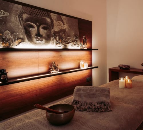 Espace spa du Jardin Sakina avec sculpture de Bouddha, étagères en bois, bougies et table de massage à Marrakech
