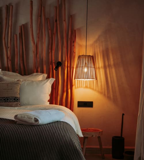 Chambre de la Suite Orangeraie au Jardin Sakina avec luminaire suspendu tressé et mur d'accent ambre chaleureux à Marrakech