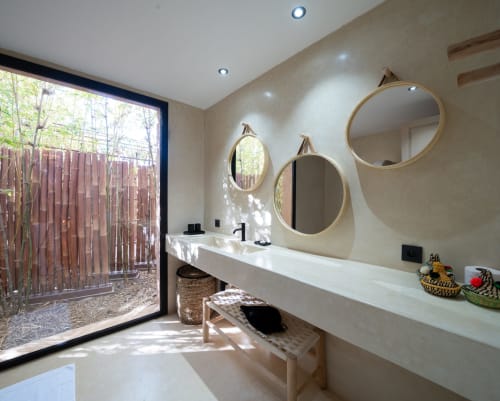 Salle de bains moderne de la Suite Jardin Sakina Bambouseraie avec miroirs ronds, vasque blanche et vue sur le jardin extérieur