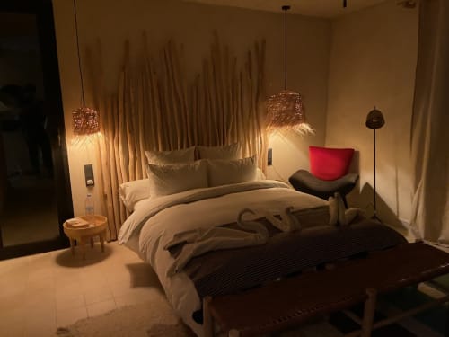 Chambre luxueuse du Jardin Sakina Marrakech avec literie crème, luminaires suspendus et coussin accent rouge surplombant la piscine