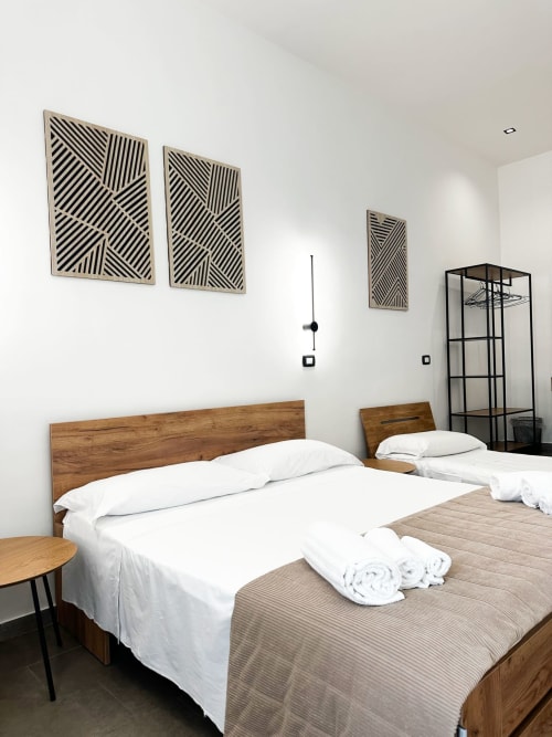 Camera tripla moderna presso I colori di Napoli B&B a Napoli con letto in legno, biancheria bianca, arte murale geometrica e arredamento minimalista
