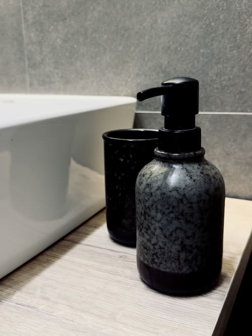 Dispenser di sapone nero e bicchiere su bancone in legno nel bagno della struttura I colori di Napoli a Napoli, Italia