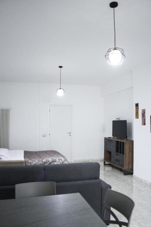 Monolocale moderno a Isernia con illuminazione contemporanea, divano nero, TV e arredamento minimalista