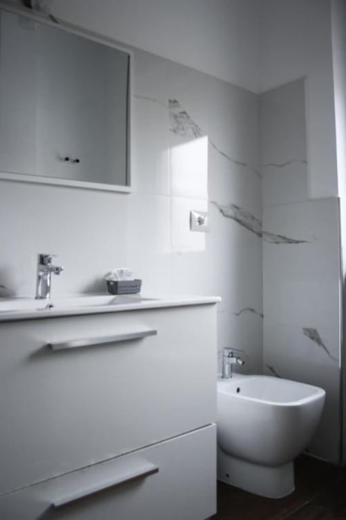 Bagno moderno nell'appartamento Ambra di Suite in Città Depandance, Isernia, con vanità bianca, specchio, toilette e zona doccia