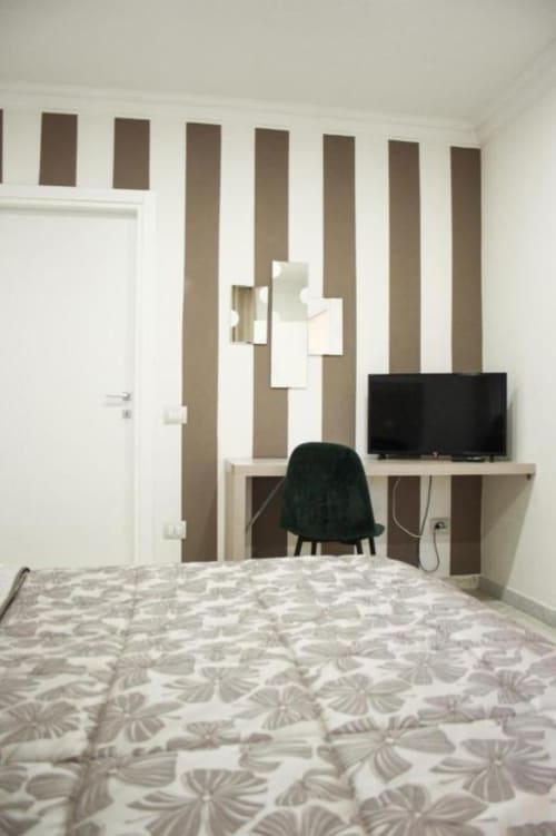 Camera moderna nell'appartamento Giada presso Suite in Città Depandance, Isernia con parete a righe, scrivania con TV e dettagli decorativi