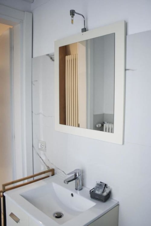 Bagno moderno con vanity bianco, rubinetto cromato e specchiera illuminata nell'appartamento Giada presso Suite in Città