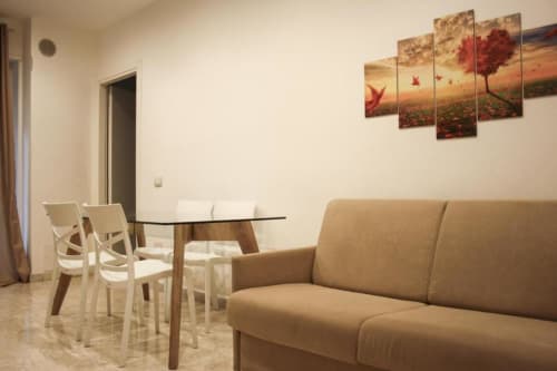 Suite moderna a Isernia con divano beige, tavolo da pranzo e opera d'arte con albero rosso