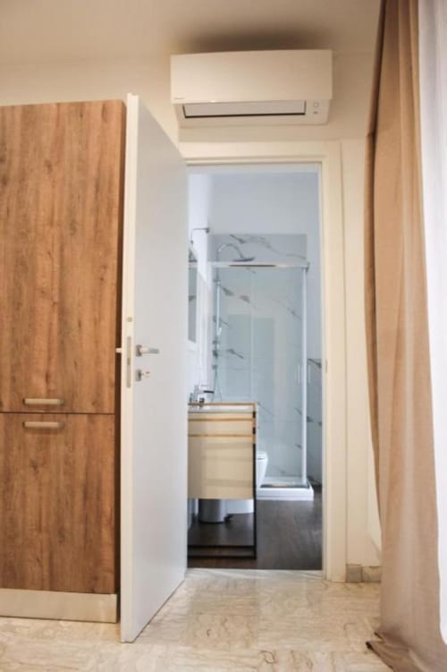 Corridoio moderno dell'appartamento a Isernia con mobile in legno, porta bianca, climatizzatore e pavimento scuro