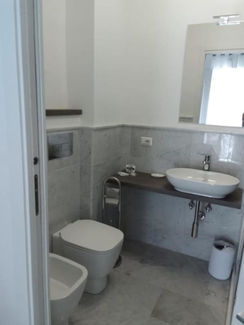 Bagno moderno nell'appartamento Ematite di Suite in Città Depandance, Isernia con toilette, lavabo ovale e pareti piastrellate