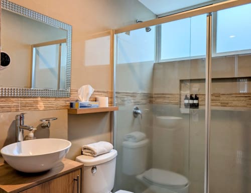 Baño moderno en el departamento Casa Donceles, Ciudad de México, con lavamanos tipo recipiente, ducha de cristal y tocador de madera.