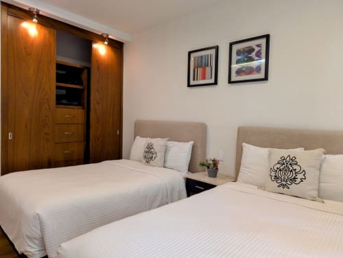 Habitación doble del apartamento Casa Donceles en Ciudad de México con ropa de cama blanca, cabeceras beige, armario de madera y cuadros en la pared