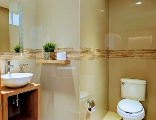 Baño moderno del apartamento Casa Donceles en la Ciudad de México con lavamanos tipo vasija, ducha de vidrio, inodoro y detalles de madera