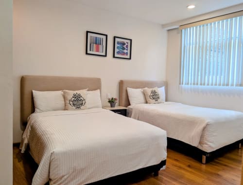 Habitación doble en el hotel Casa Donceles de México con dos camas, cabeceras color arena, ropa de cama blanca y piso de madera