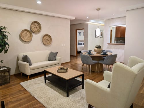 Moderno salón de Casa Donceles en Ciudad de México con sofás color crema, mesa de madera y cestos tejidos en la pared