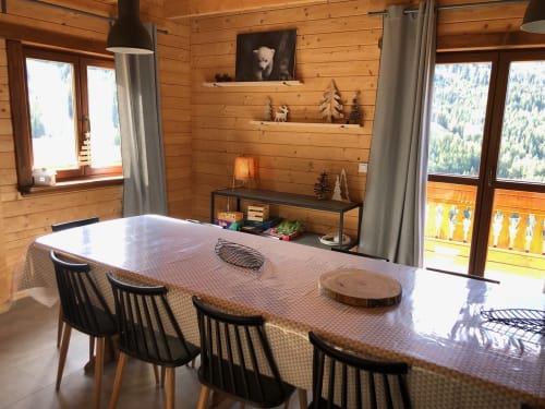Salle à manger du chalet en bois avec vue sur les montagnes, chaises noires, longue table, étagères décorées aux Chalets d'Aline, La