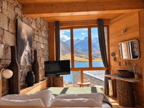 Chambre de luxe en chalet en bois au Tignes Lake Lodge, avec vue sur la montagne et le lac par de grandes fenêtres