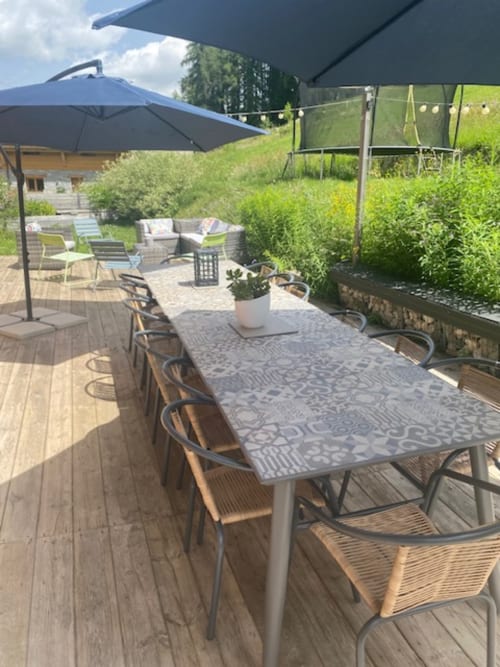 Terrasse extérieure des Chalets d'Aline avec table de dining, parasols et vue sur les montagnes à La Plagne