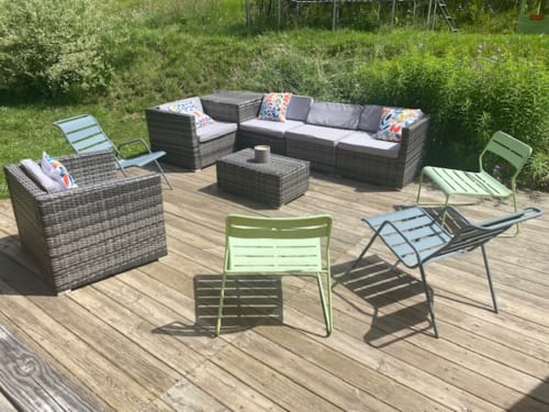 Coin salon extérieur aux Chalets d'Aline à La Plagne avec canapé en rotin, chaises colorées et terrasse en bois
