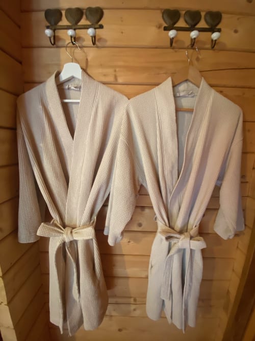 Peignoirs en coton crème suspendus à des crochet en bois aux Chalets d'Aline, La Plagne Tarentaise