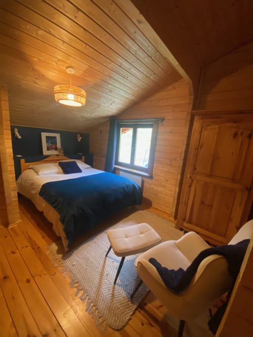 Chambre cosy en bois aux Chalets d'Aline, La Plagne, avec lit queen-size, mur d'accent sombre et ambiance lodge alpin