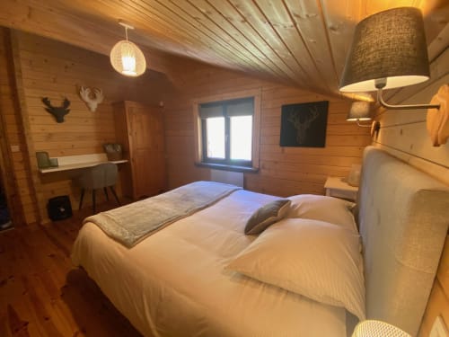 Chambre douillette du chalet en bois aux Chalets d'Aline à La Plagne avec lit queen-size, bureau et décor de chasse rustique