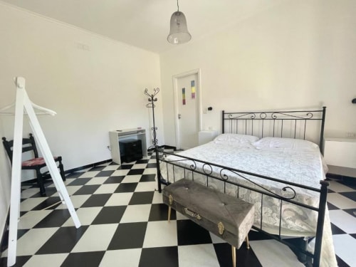 Spacious double bedroom at Palazzo di Donna with black and white checkered floor, metal bed frame, and pendant lighting