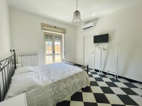 Bright double bedroom at Palazzo di Donna with black and white floor, modern amenities, and balcony access to park views