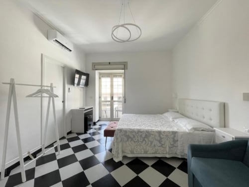 Camera matrimoniale moderna al Palazzo di Donna con pavimento a scacchi bianco e nero, letto bianco e balcone vista parco