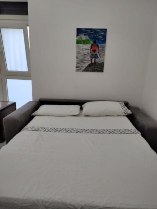 Camera da letto al Palazzo di Donna con letto matrimoniale, due cuscini, finestra e opera d'arte marina sulla parete