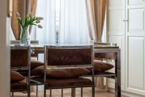 Modern dining area in UrbanFlat Roma apartment with glass table, brown chairs, fresh flowers, and city view through windows